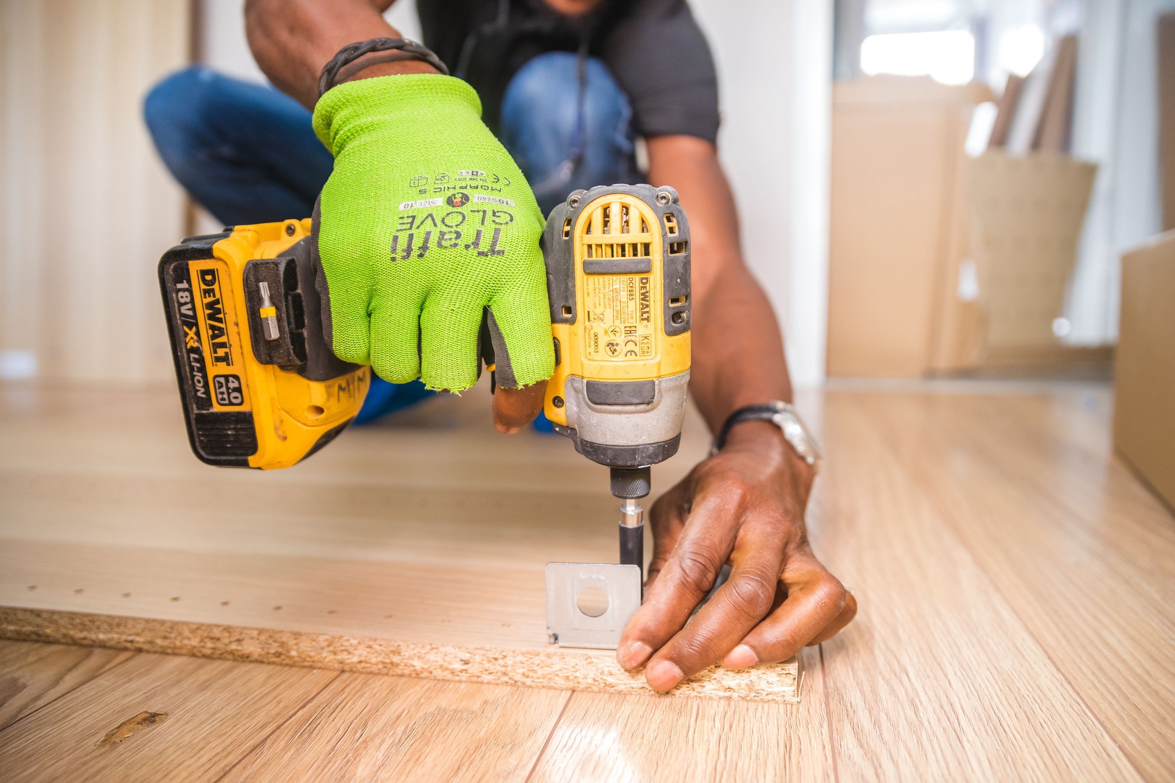 Close view of a tradesperson's gloved hands using a cordless power tool on a timber panel